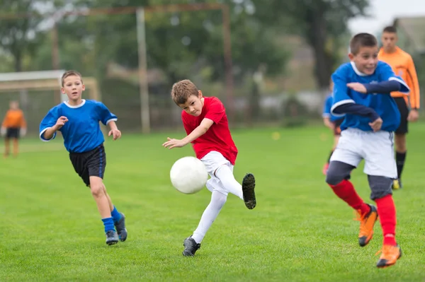 Мальчик пинает футбол — стоковое фото