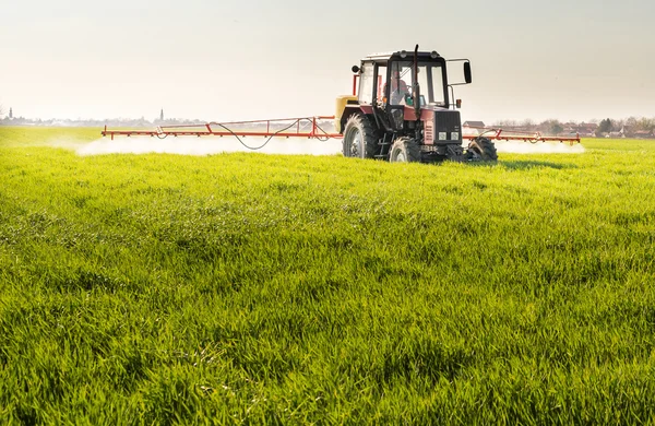 Traktor postřiku pšeničné pole — Stock fotografie