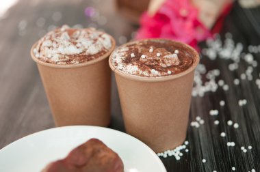 İki bardak kahve siyah masada bir nosegay ile