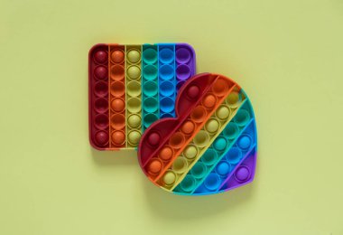 Renk, çocuklar için stres önleyici bir oyuncak. Sarı arka planda izole edilmiş gökkuşağı kalbi .2 oyuncak kare şeklinde ve kalp şeklinde..