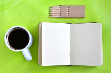 Açık boş defter, fincan kahve ve yeşil arka plan (düz yattı üzerinde boya kalemi)