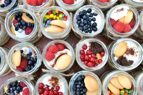 Sobremesa doce e saudável: muitos copos cheios de creme e frutas coloridas minúsculas — Fotografia de Stock