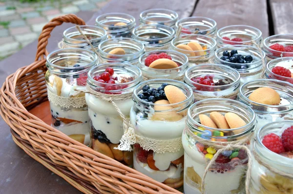 Dolce, fresco e sano dessert di frutta in molti barattoli di imbottigliamento in cesto di vimini — Foto Stock