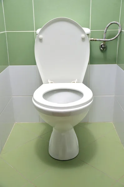 Flush toilet with white and green tiles in background — Stock Photo, Image