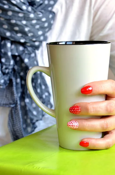 Parmaklarının üzerinde kırmızı çivi ile kız beyaz Kupası, closeup tutun