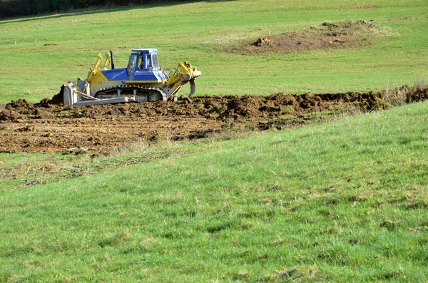 Gelb blaue Planierraupe arbeitet auf dem Feld — Stockfoto