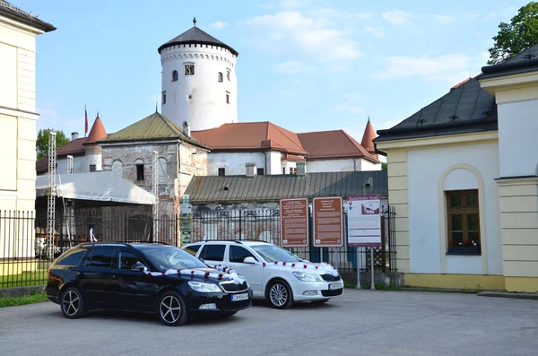 Two cars dedicated for wedding guests decorated by white ribbon on car park in front of the Budatin castle. — Stock Photo, Image