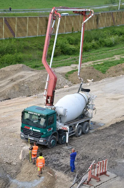 Trzech pracowników i transportu betonu ciężarówka z pompa do betonu gotowy do użycia. Ta działalność związana jest z kolei procesu odbudowy. — Zdjęcie stockowe