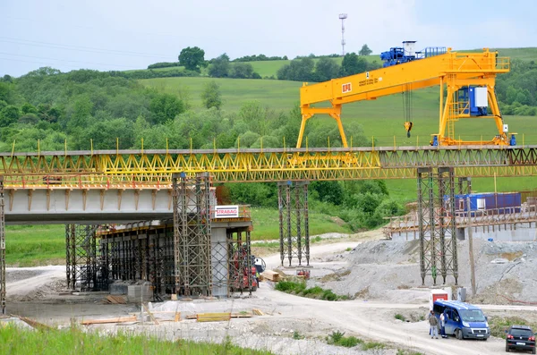 Gelber Brückenkran auf der Baustelle der slowakischen Autobahn d1. Außer dem Kran gibt es einige Arbeiter und Autos. — Stockfoto