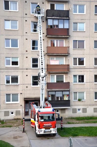 Пожарные в действии, мужчина в телескопической корзине пожарной машины. Блок квартир на заднем плане . — стоковое фото