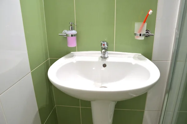 Lavabo bianco, portasapone e spazzolino in vetro nel bagno piastrellato bianco verde — Foto Stock