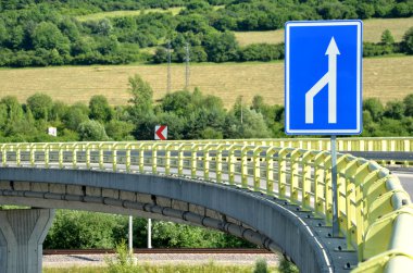 Kırsal, beyaz ok trafik işareti ön planda eğri besleyici yolda  