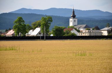 Köy, ormanlık tepelerde arka plan, sarı alan tahıl ön planda bir parçası olarak Hıristiyan Kilisesi