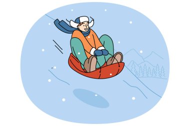 Genç çocuk kış kayak merkezinde dinleniyor, şişme kızakla karla kaplı tepeden kayıyor. Mutlu genç adam kış mevsiminde, tatilde ya da tatilde aktif bir hayat sürüyor.