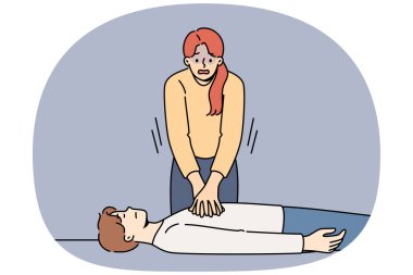 Kadın gergin, adama kalp masajı yapıyor bayılmış, göğüs kaslarına baskı yapıyor. Ani kalp yetmezliği olan ya da kardiyo fonksiyonlarında bozukluk olan birinin ilk yardım ve kurtarılması eğitimi.