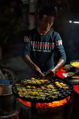 Mandalay. Myanmar. 23 Kasım 2016. Bir sokak aşçısı Ulusal Bayram 'da özel bir tavada bıldırcın yumurtasından kızarmış yumurta hazırlar. Bu yemek bu ülkede en popüler yemektir..