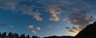 - Rusya. Doğu Sibirya 'nın güneyi. Akşam vakti kasvetli günbatımı bulutları Yazın gökyüzü Doğu Sayan 'ın sıradağları üzerinde.