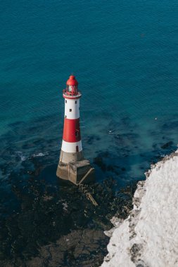 Bir Beachy Head Deniz feneri ve tebeşir kayalıklarının renkli gündoğumunda İngiltere 'de, Eastbourne yakınlarında alçak gelgitle çekilmiş manzara fotoğrafı.