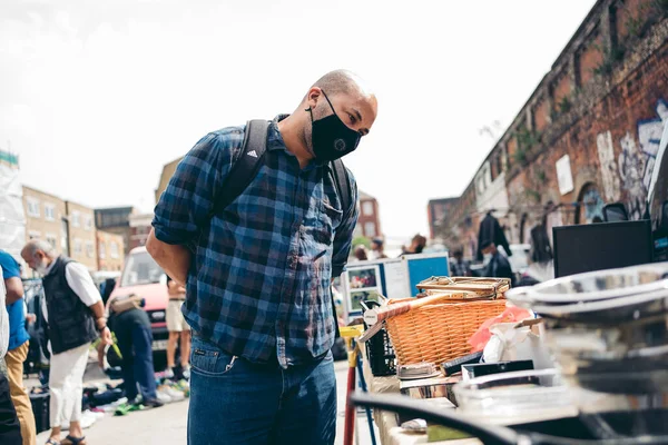 Brick Lane East London 2020 マスクをした男がヴィンテージマーケットで様々な商品を売買する — ストック写真