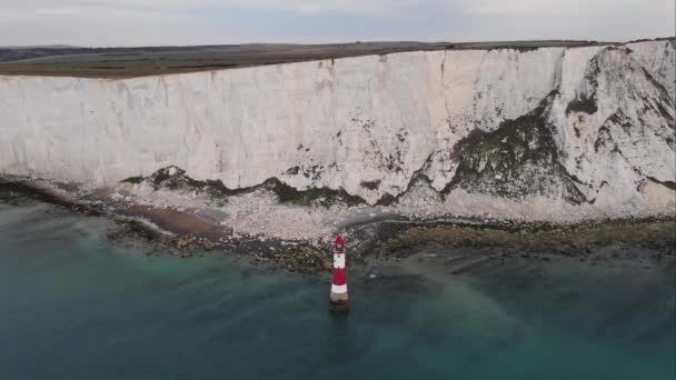 ビーチヘッド灯台とチョーク崖の風景空中ドローン映像英国の低潮位でカラフルな日の出 イーストボーンの近く — ストック動画