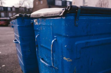 Batı Londra 'da toplanmayı bekleyen kapalı mavi çöp kutuları.