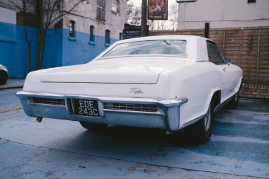Isleworth, Batı Londra (124; İngiltere - 2021.03.14: Vintage Retro 1965 Beyaz Buick Riviera GS Yağmurdan sonra güneşli bir günde park edilmiş mükemmel konumda