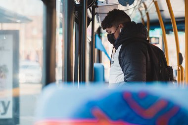 Shepherd 's Bush, Londra -124; İngiltere - 2021.03.22: Coronavirus salgını sırasında otobüsten çıkan tıbbi maskeli genç adam