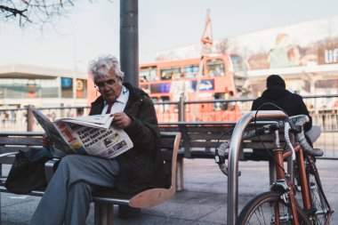 Shepherd 's Bush, Londra 124; İngiltere - 2021.03.22: Bisiklet gazete okuyan beyefendilerin yanına park edildi