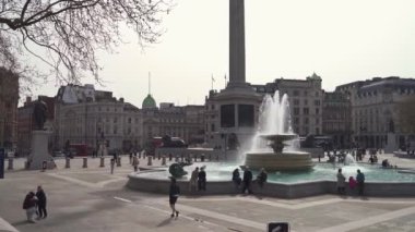 İnsanlar Coronavirus Kilitlemesi sırasındaki güneşli bahar gününde Trafalgar Meydanı çeşmelerinde takılıyor.