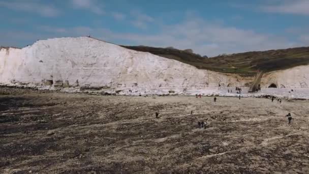 Uitzicht vanuit de lucht op wandelaars, wandelen aan het strand aan zee tijdens het laagwater bij Hope Gap. Natuurreservaat Seaford Head — Stockvideo