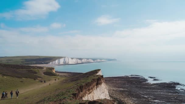 Timelapse de personas recorriendo los senderos de las Siete Hermanas, la Reserva Natural de los Senderos Clifftop Vista de los acantilados de tiza y el mar del Canal de la Mancha desde el borde. Sur de Inglaterra — Vídeos de Stock