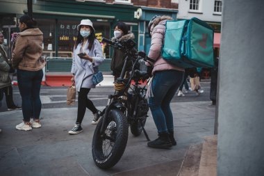 Soho, Londra the 124; İngiltere - 2021.04.16: Yeni düzeni bekleyen bisikletli teslimatçı adam şoförü. Kargo Servisi