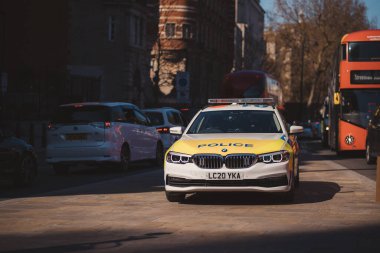 Westminster, Londra the 124; UK - 2021.04.17: Polis arabası BMW kaldırıma park etti kırmızı çift katlı otobüsün yanına.