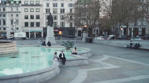 Gente pasando el rato en las fuentes de Trafalgar Square en el cálido y soleado Primavera de Europa durante Coronavirus Lockdown — Vídeos de Stock