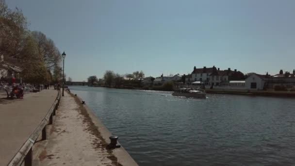 Barco pasando por los otros barcos amarrados junto a las hermosas casas en el río Támesis en Staines — Vídeos de Stock
