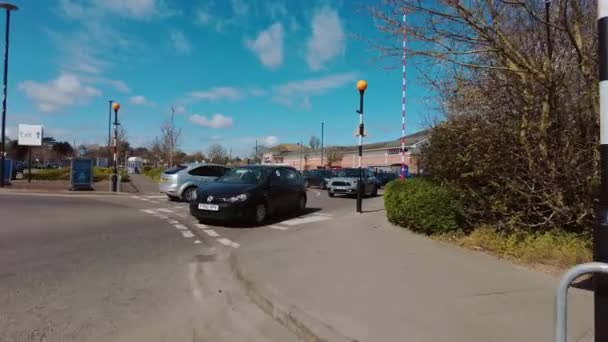 Auta opouštějící příjezd na rušné Tesco extra supermarket parkování za slunečného dne — Stock video