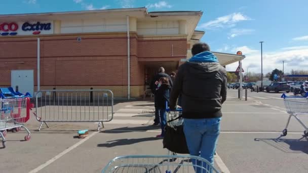 People waiting in the queue to enter the Tesco Extra Superstore with shopping trolleys — Stock Video
