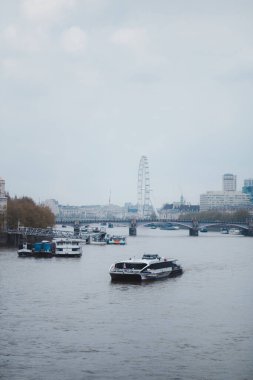 Westminster, Londra (124; İngiltere - 2021.05.02: Ünlü Londra Göz (Millennium Wheel), Londra Thames Nehri 'nin güney kıyısında dönme dolap. Thames Clippers nehir otobüsünün yanındaki Ay Kırpıcı Uber teknesiyle.