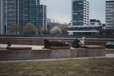 Westminster, Londra (124; İngiltere - 2021.05.02: Yorgun adam yanında sırt çantasıyla dolgu parkında yatıyor
