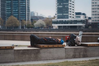 Westminster, Londra (124; İngiltere - 2021.05.02: Yorgun adam yanında sırt çantasıyla dolgu parkında yatıyor