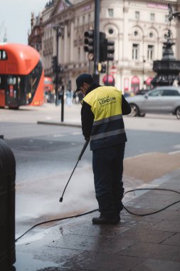 Westminster, Londra the 124; İngiltere - 2021.05.02: Kaldırımları yüksek basınçlı temizleyen adam