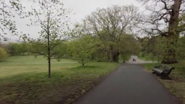 Bulutlu bahar gününde Greenwich parkında yürüyorum.