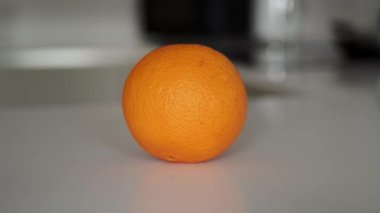 Beyaz mutfak tezgahındaki tek bir portakalın görüntüsünü yakınlaştır.