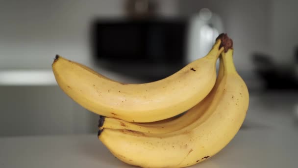 Powiększ materiał z bandą żółtych bananów na białym blacie kuchennym. — Wideo stockowe
