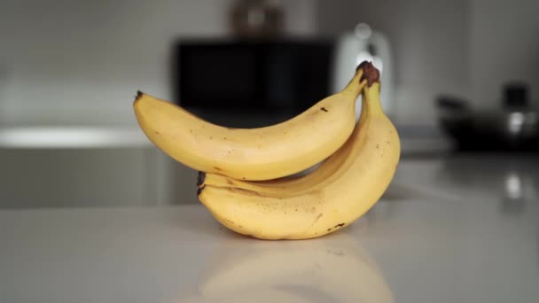 Ampliar las imágenes de un montón de plátanos amarillos en la encimera de la cocina blanca — Vídeo de stock