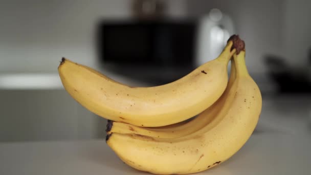 Powiększ materiał z bandą żółtych bananów na białym blacie kuchennym. — Wideo stockowe