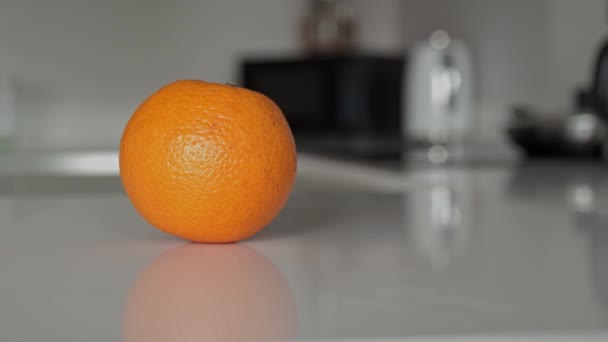 Οριζόντιο τηγάνι στο αριστερό πλάνο ενός μόνο πορτοκαλιού στον πάγκο της κουζίνας — Αρχείο Βίντεο