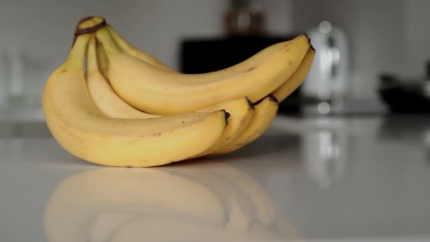 Padella orizzontale a sinistra di un mazzo di banane gialle sul piano di lavoro della cucina bianca — Video Stock