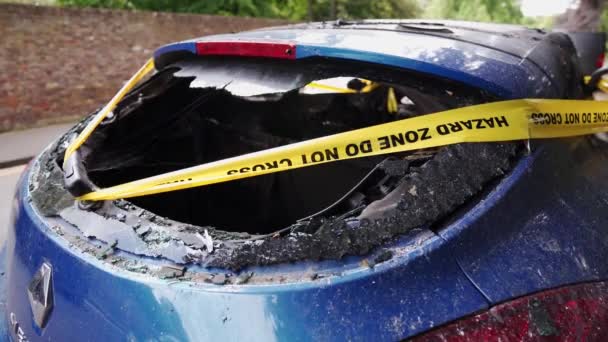 Um abandonado, roubado queimado carro azul estacionado no estacionamento lateral amarrado com amarelo não cruzar faixa — Vídeo de Stock