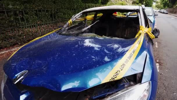 Un abandonado, robado quemado coche azul estacionado en el lugar de estacionamiento lateral atado con amarillo no cruzar la raya — Vídeo de stock